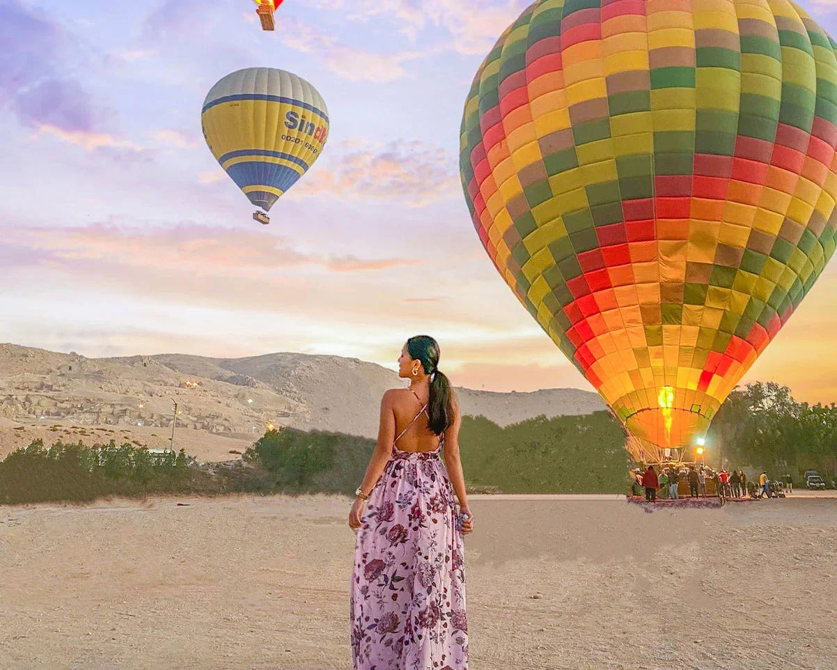 A traveler watching hot air balloons launch at sunrise near Luxor