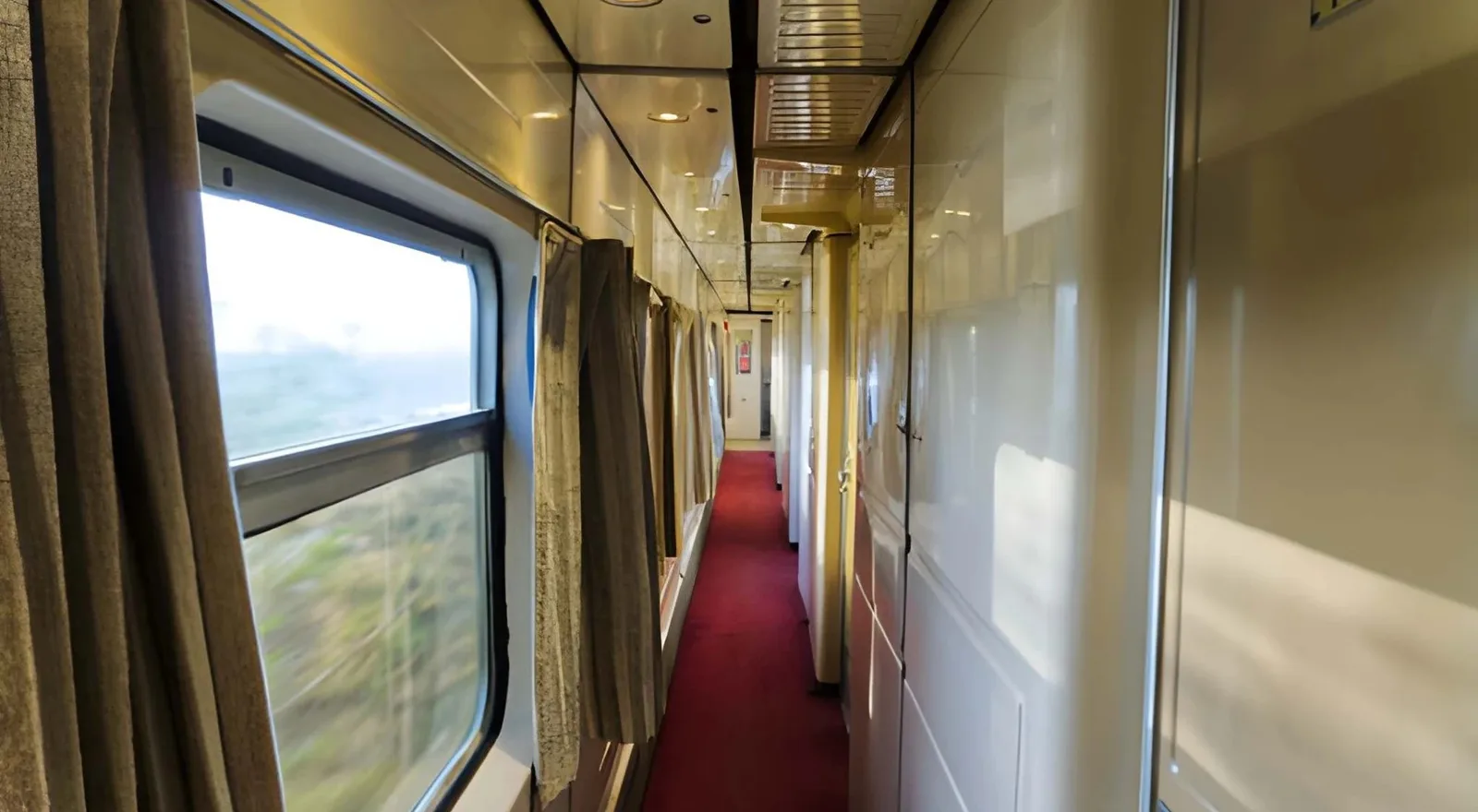 Pasillo de un coche cama con ventanas al paisaje y las cabinas a un lado