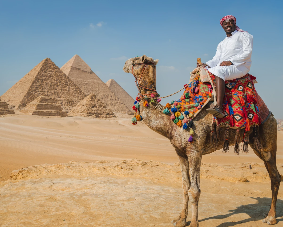 A tourist riding a camel in front of the pyramids