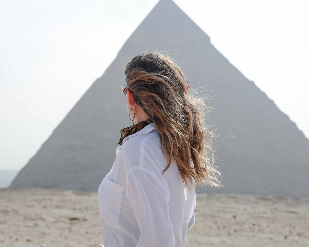 A tourist taking a photo from behind in front of the pyramids