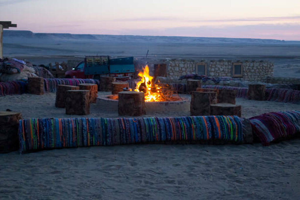 Bedouin desert camp in Egypt with traditional seating and campfire at sunset